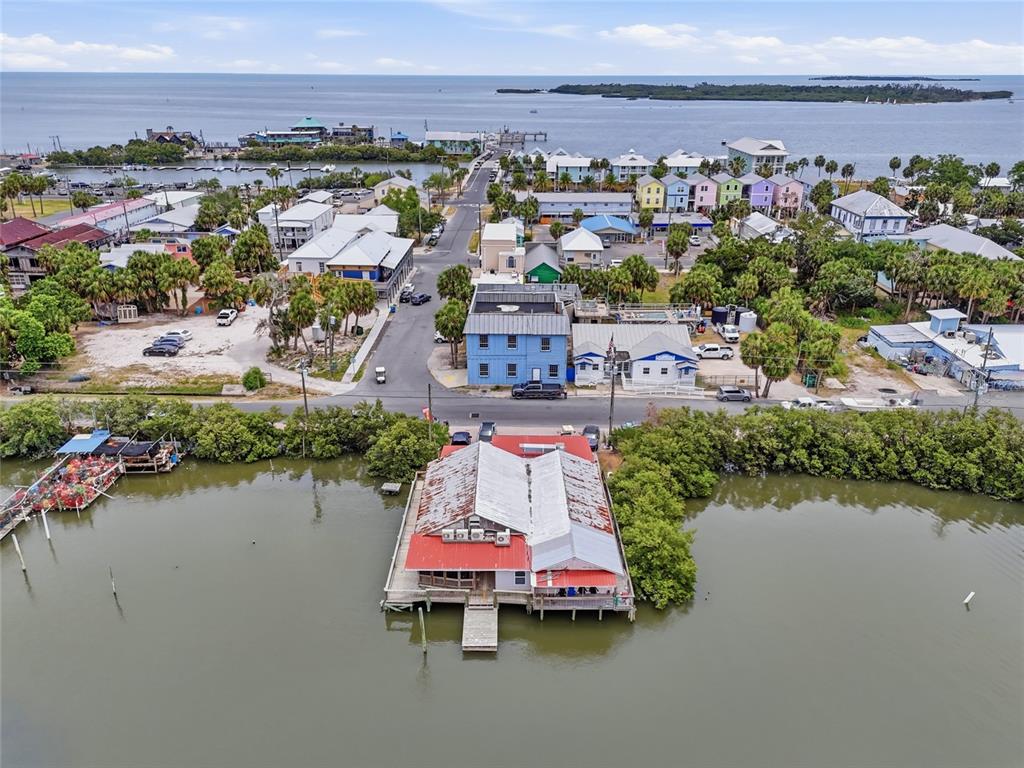 An aerial view shows a waterfront building with a red roof and surrounding town structures — 505 3RD STREET, CEDAR KEY, FL