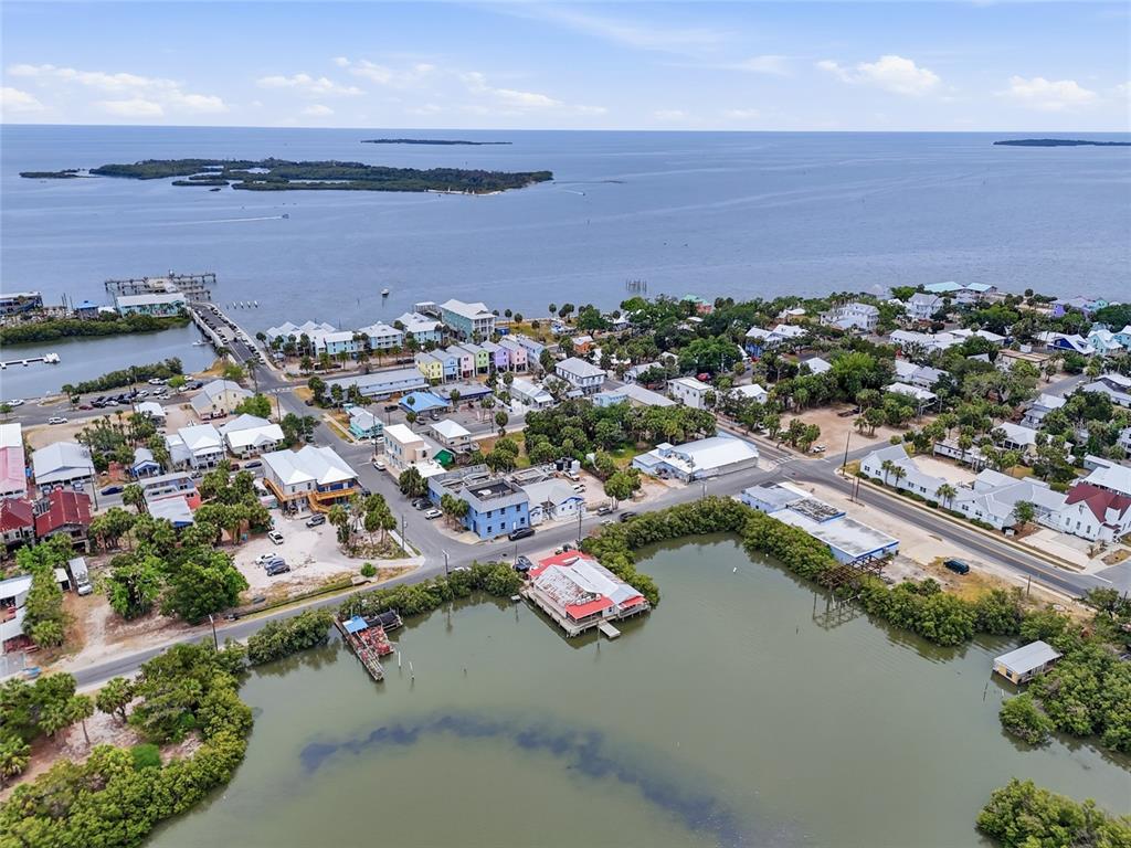 An aerial view shows a coastal town with colorful houses, a marina, and a bay — 505 3RD STREET, CEDAR KEY, FL