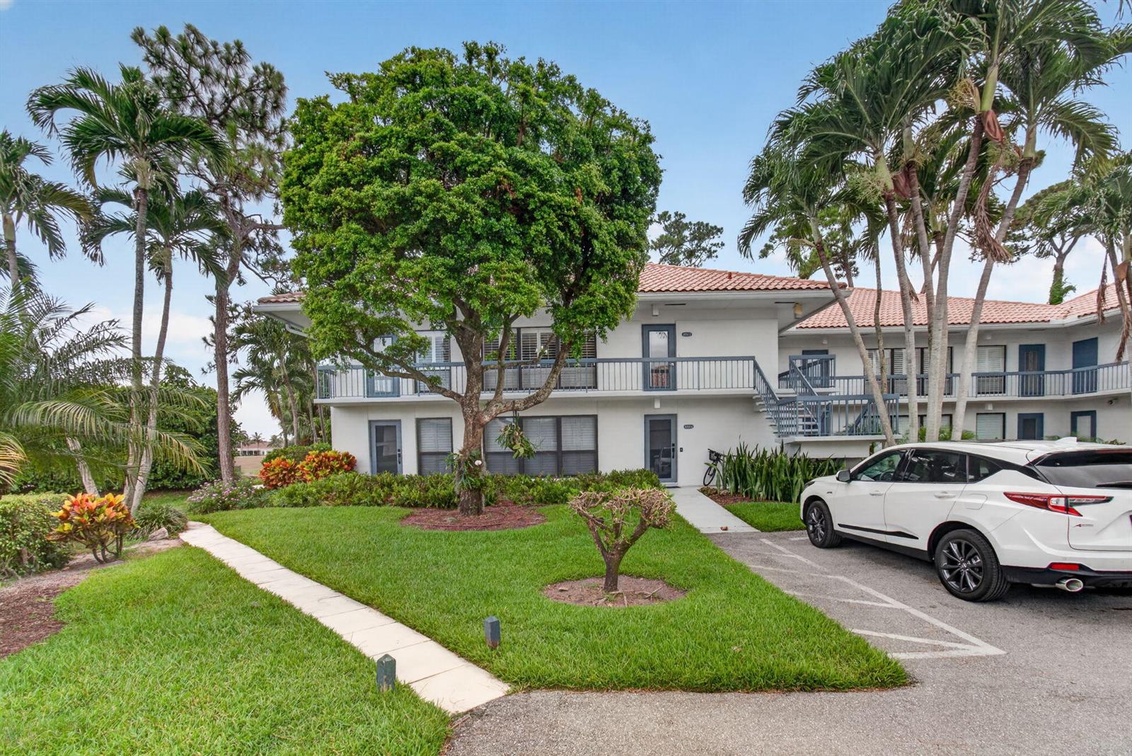 A two-story apartment building with a white exterior, tile roof, and a large central tree — 4084 N Quail Ridge Drive Unit B, Boynton Beach FL 33436, BOYNTON BEACH, FL