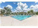 An outdoor rectangular swimming pool is surrounded by a light-colored concrete deck under a sky — 17010 YELLOW PINE STREET, WIMAUMA, FL