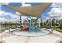 A playground area features a circular splash pad covered by a large triangular shade sail — 17010 YELLOW PINE STREET, WIMAUMA, FL