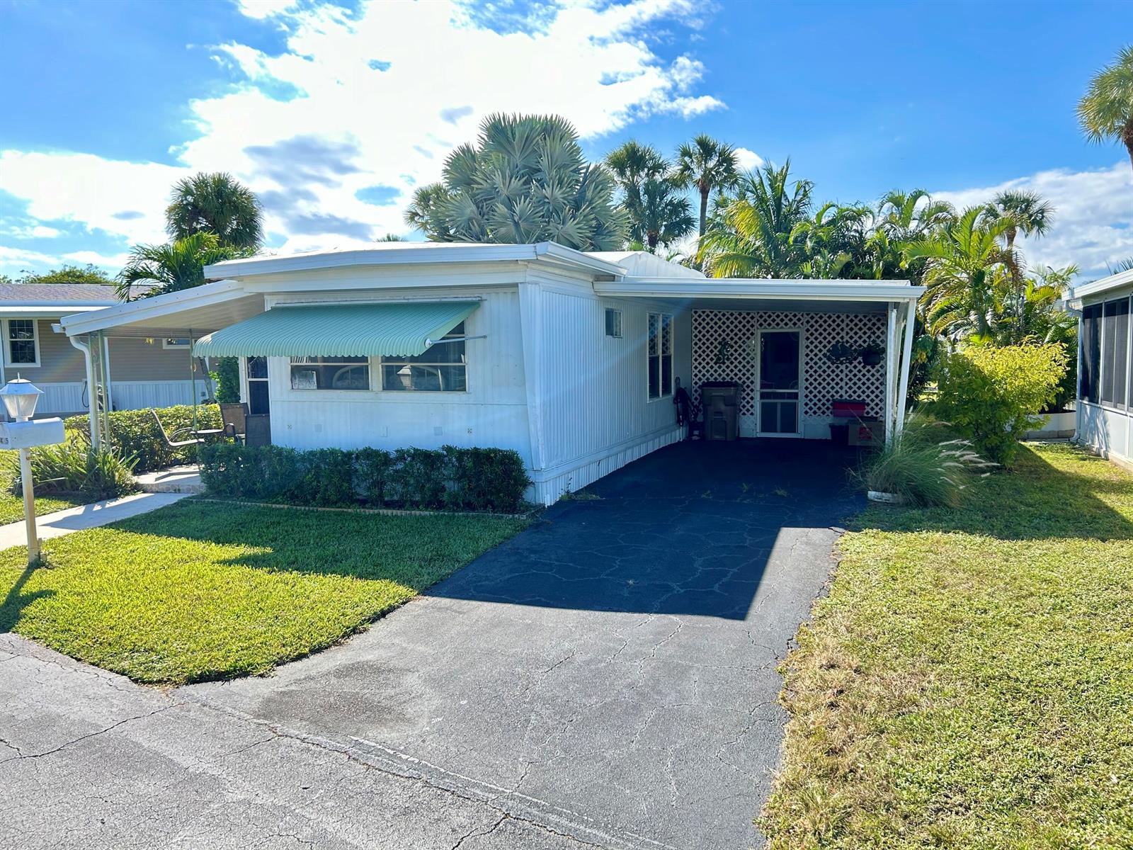 A white mobile home features a green awning, a carport, and a paved driveway — 425 E Bougainvillea Drive, Deerfield Beach FL 33442, DEERFIELD BEACH, FL