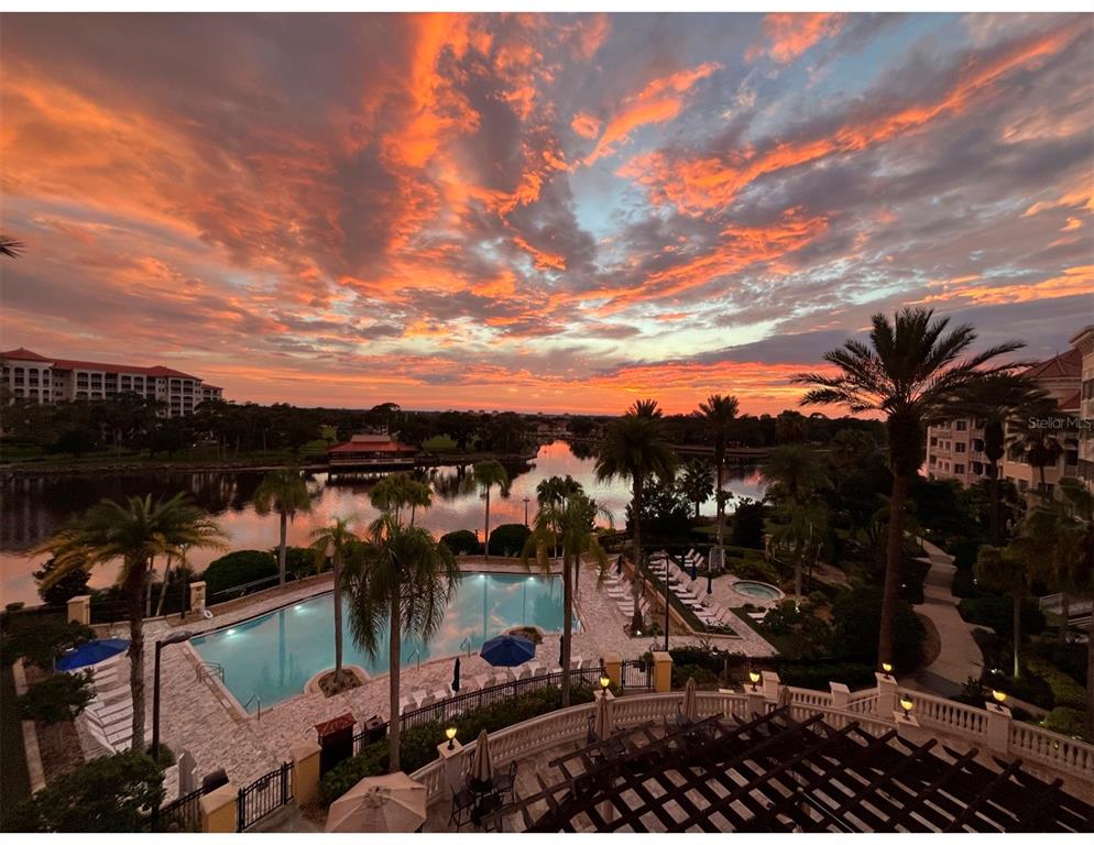An elevated view of a swimming pool and lake at sunset with surrounding resort buildings — 102 YACHT HARBOR DRIVE UNIT 467, PALM COAST, FL
