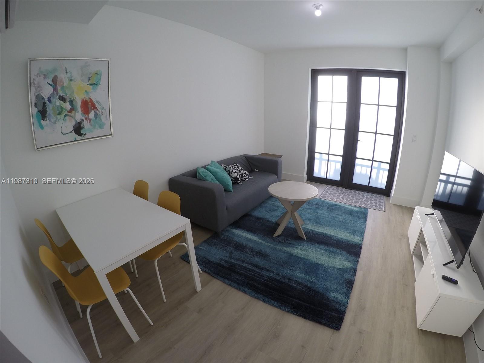 A living and dining area features a grey sofa, yellow chairs, and a blue rug — 4100 SW 64th Ave # 409, Davie FL 33314, DAVIE, FL