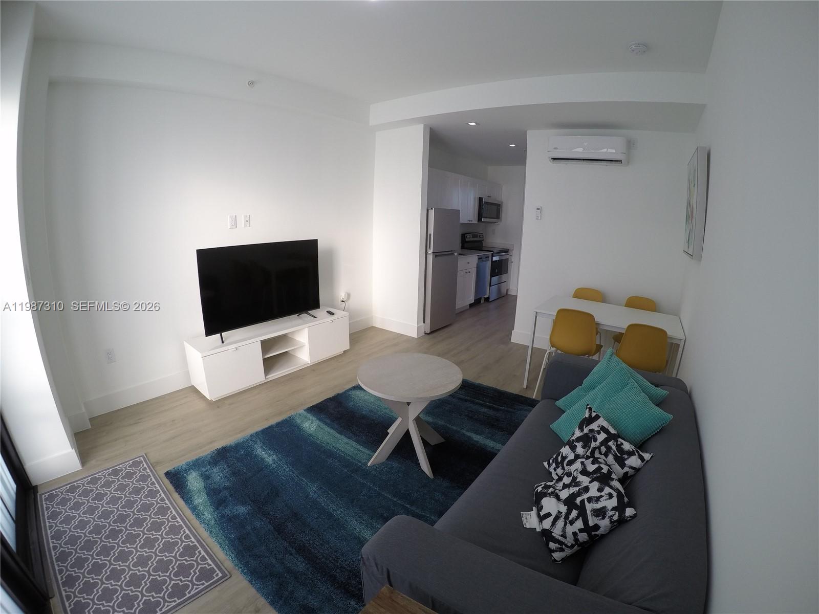 A living room with a grey sofa, blue area rug, and an adjacent kitchen area — 4100 SW 64th Ave # 409, Davie FL 33314, DAVIE, FL