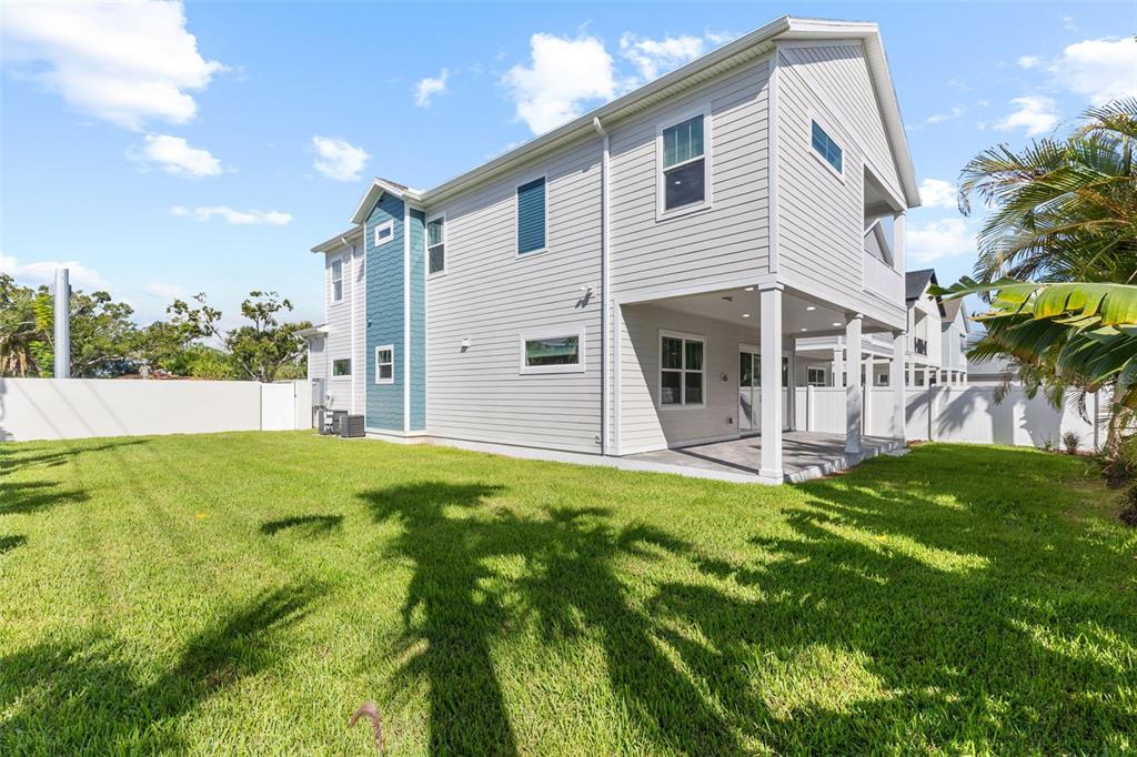 A two-story house with light gray siding and a blue accent wall features a backyard — 3801 71ST STREET N, ST PETERSBURG, FL
