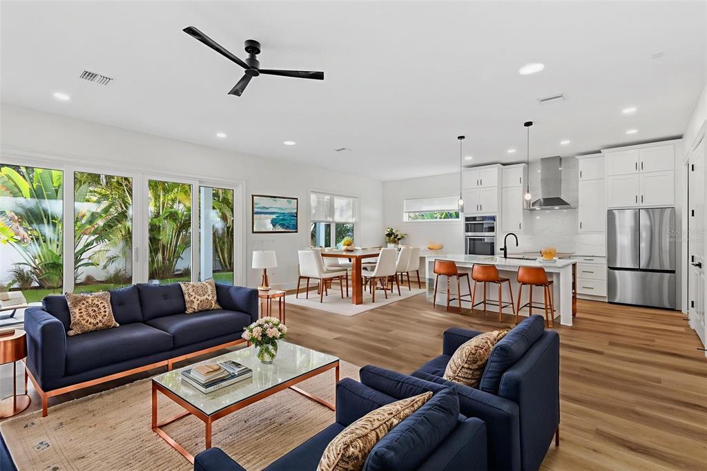 An open-concept living and dining area features a modern kitchen with white cabinetry and island — 3801 71ST STREET N, ST PETERSBURG, FL