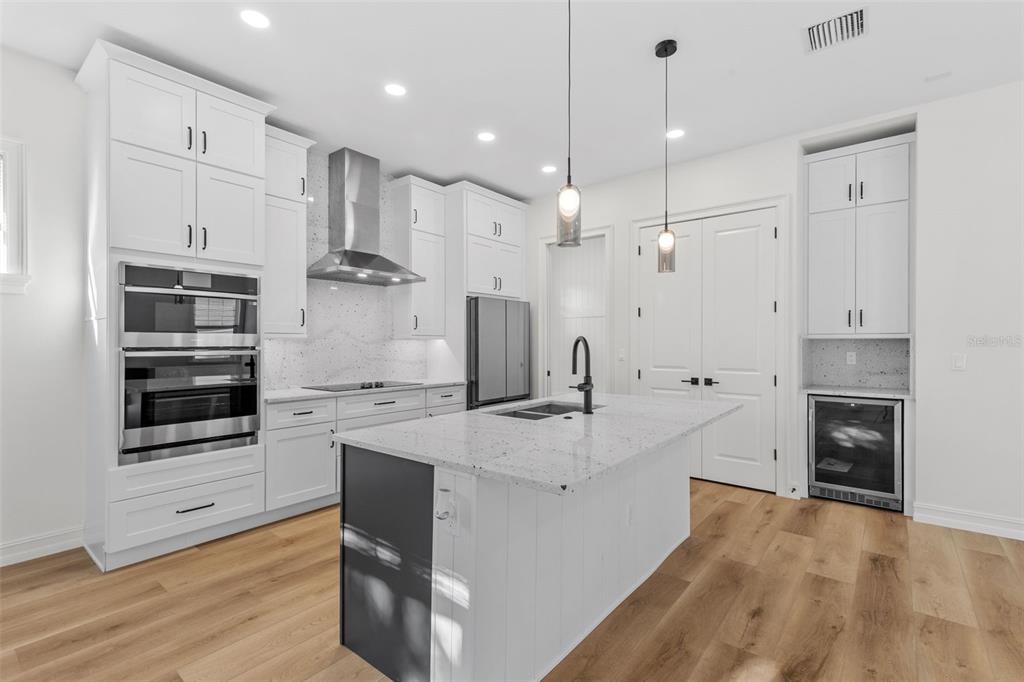 A modern kitchen features white cabinetry, a granite-topped island, stainless steel appliances, and wood flooring — 3801 71ST STREET N, ST PETERSBURG, FL