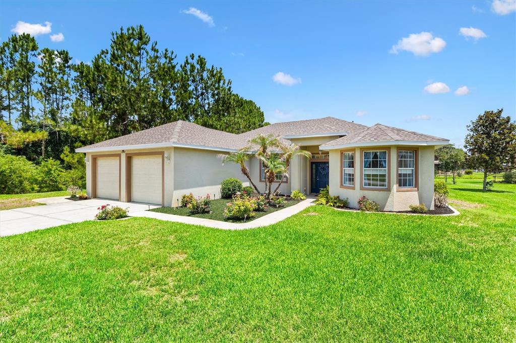 A single-story house with a two-car garage, tan stucco exterior, and a landscaped front yard — 12107 EAGLE POINT COURT, LEESBURG, FL