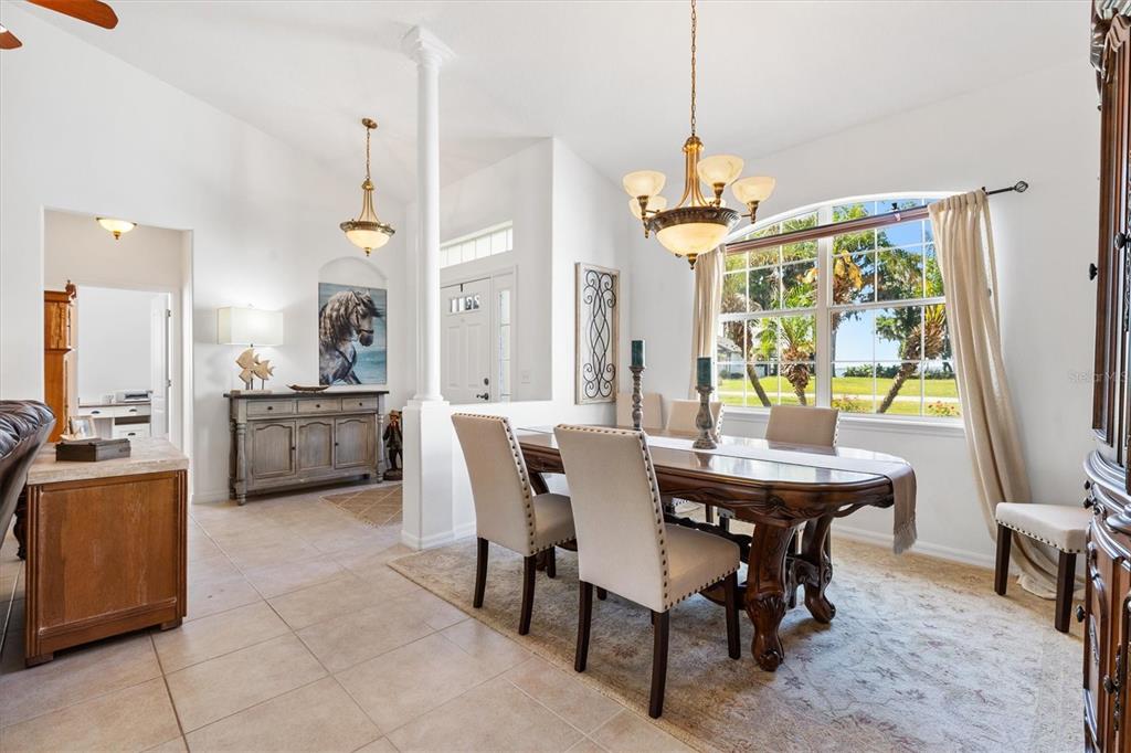 A dining room features a wooden table, upholstered chairs, a chandelier, and a large window — 12107 EAGLE POINT COURT, LEESBURG, FL