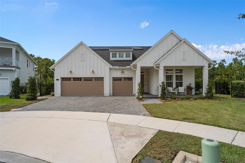 A white house with a three-car garage and a covered front porch under a blue sky — 3135 VANGUARD COURT, ST CLOUD, FL