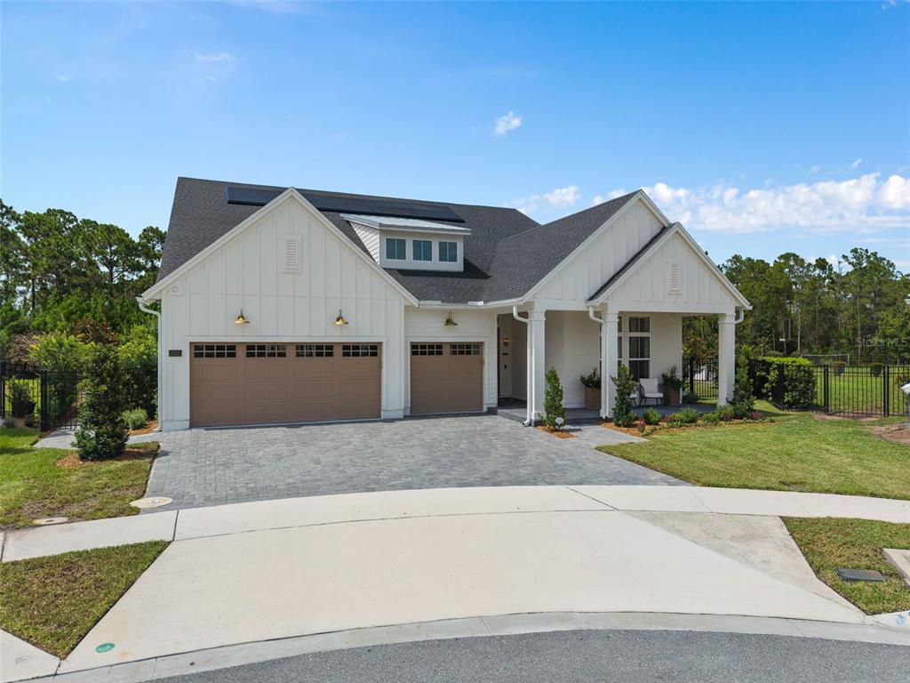 A white farmhouse-style house with a three-car garage and a paved driveway — 3135 VANGUARD COURT, ST CLOUD, FL