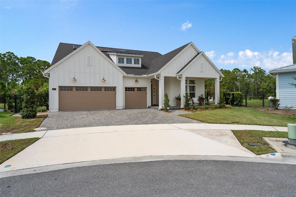 A white farmhouse-style house with a three-car garage and a paved driveway — 3135 VANGUARD COURT, ST CLOUD, FL