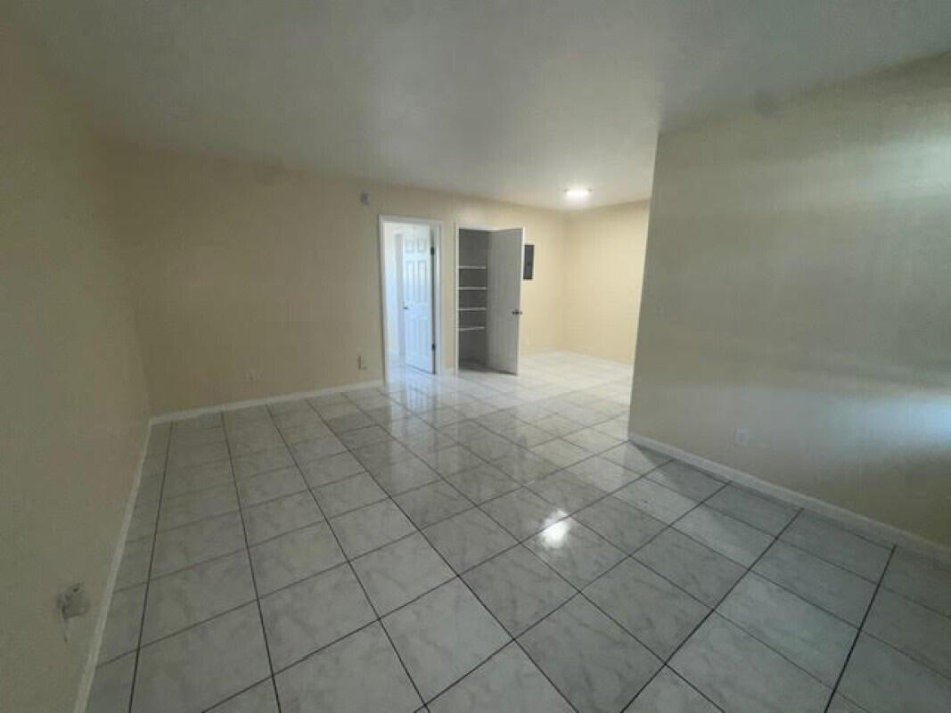 An empty room with light-colored tile flooring, beige walls, and an open closet door — 1751 NE 31st Street # 26, Pompano Beach FL 33064, POMPANO BEACH, FL