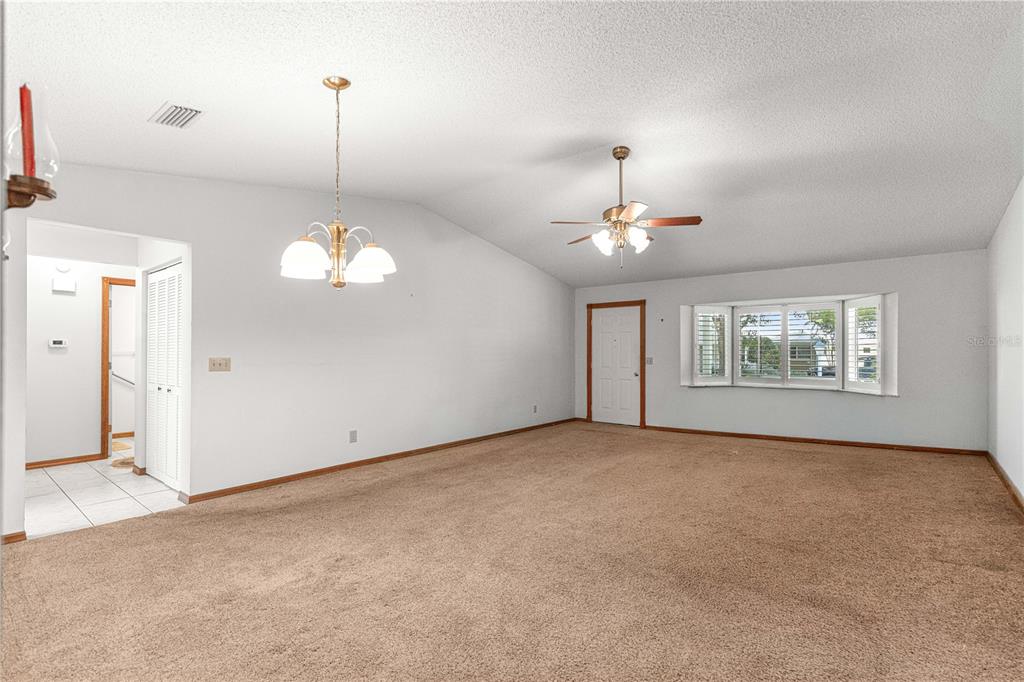 A spacious living room features beige carpeting, white walls, a ceiling fan, and a bay window — 8802 SW 92ND STREET UNIT A, OCALA, FL