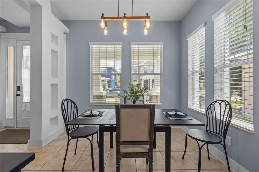 A dining area with a dark table, three chairs, a light fixture, and large windows — 3537 PICKERELL PLACE, NEW PORT RICHEY, FL