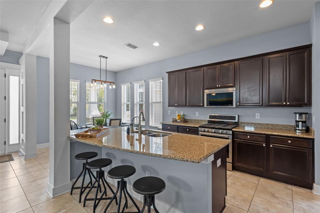 A kitchen features dark wood cabinets, granite countertops, a center island, and bar stools — 3537 PICKERELL PLACE, NEW PORT RICHEY, FL