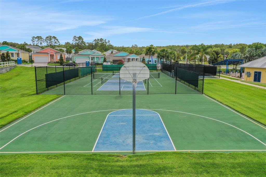 A basketball court sits in the foreground with tennis courts and houses in the background — 1038 FIESTA KEY CIRCLE, LADY LAKE, FL