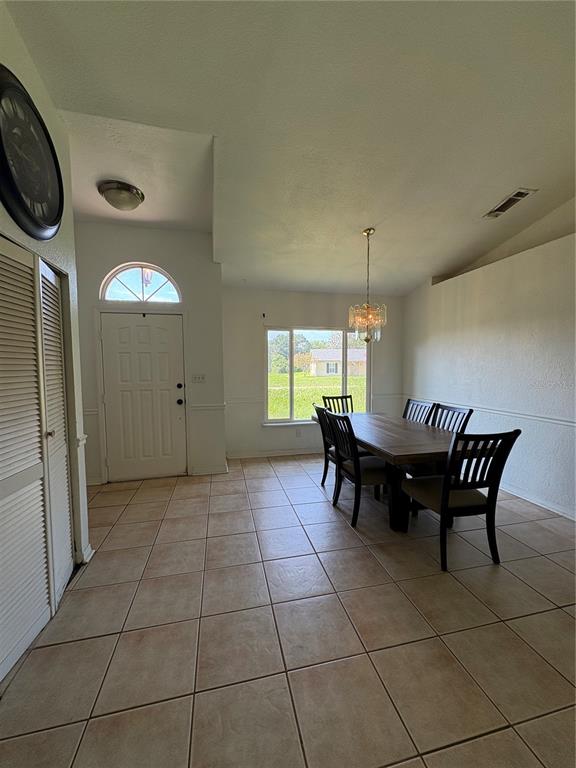 A dining area features tile flooring, a wooden table with chairs, and a front door — 2302 BELEN DRIVE, DELTONA, FL