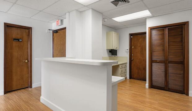 A reception area features a white desk, wood-look flooring, and several wooden doors — 50 NE 26th Street, Pompano Beach FL 33064, POMPANO BEACH, FL