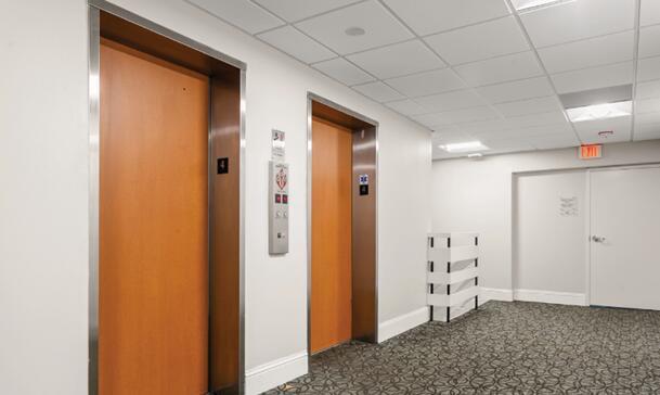 A hallway features two wood-paneled elevator doors, a patterned carpet, and a white door — 50 NE 26th Street, Pompano Beach FL 33064, POMPANO BEACH, FL