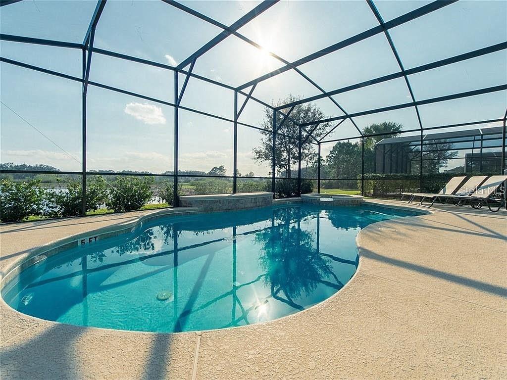 A screened-in swimming pool and spa with lounge chairs on a concrete deck — 4357 ACORN COURT, DAVENPORT, FL
