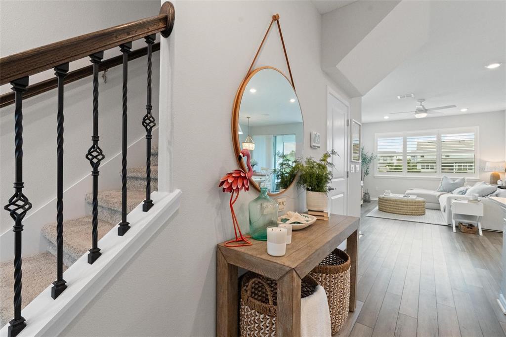 An entryway features a wooden console table, a round mirror, and a staircase with railings — 351 SURFSIDE AVENUE NE, ST PETERSBURG, FL