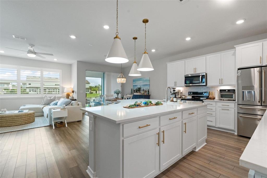 A white kitchen with a large island and pendant lights opens into a living area — 351 SURFSIDE AVENUE NE, ST PETERSBURG, FL