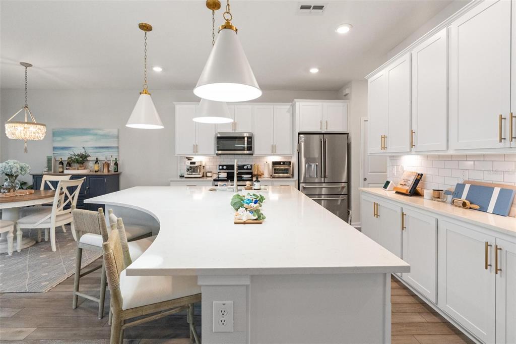 A modern kitchen features white cabinetry, a large curved island, and stainless steel appliances — 351 SURFSIDE AVENUE NE, ST PETERSBURG, FL