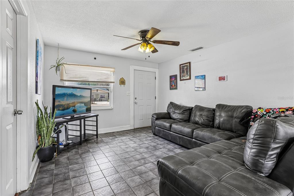 A living room features dark tile flooring, a leather sectional sofa, and a ceiling fan — 3435 SWINDELL ROAD, LAKELAND, FL