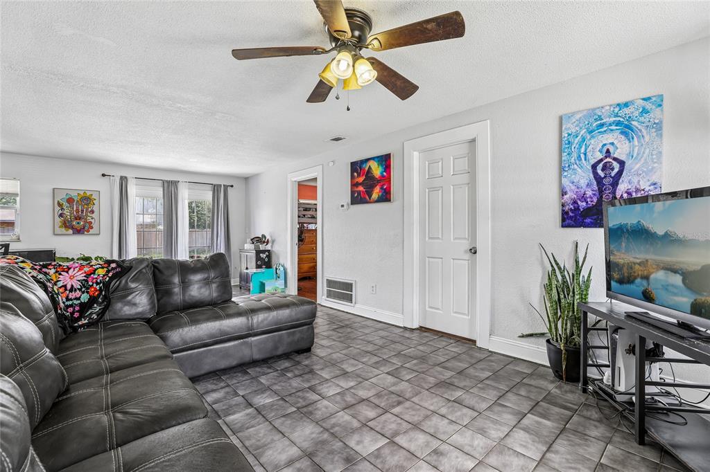 A living room features a grey sectional sofa, tiled floors, a ceiling fan, and wall art — 3435 SWINDELL ROAD, LAKELAND, FL