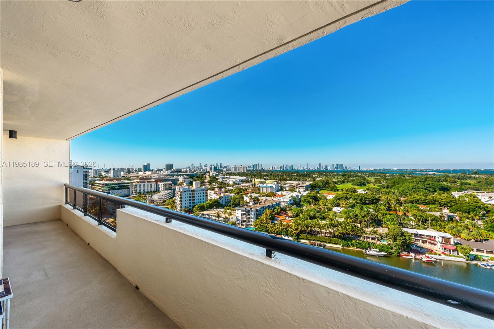 A high-rise balcony overlooks a city skyline, lush green trees, and a waterway — 2555 Collins Ave # 2002, Miami Beach FL 33140, MIAMI BEACH, FL