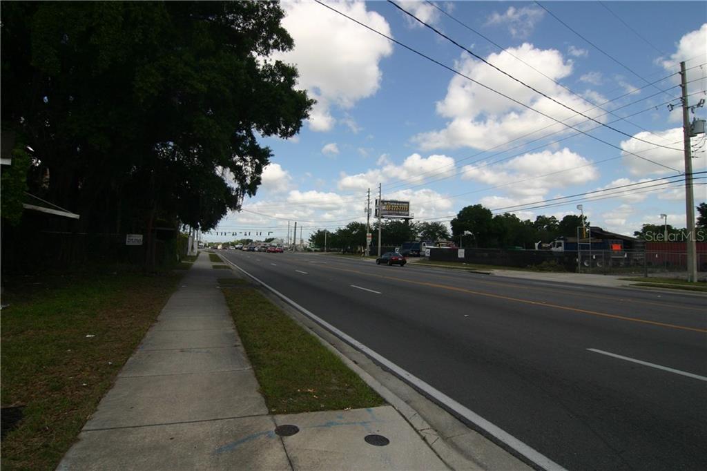 A paved sidewalk runs alongside a multi-lane road under a bright, cloudy sky — 2720 OLD WINTER GARDEN ROAD, ORLANDO, FL