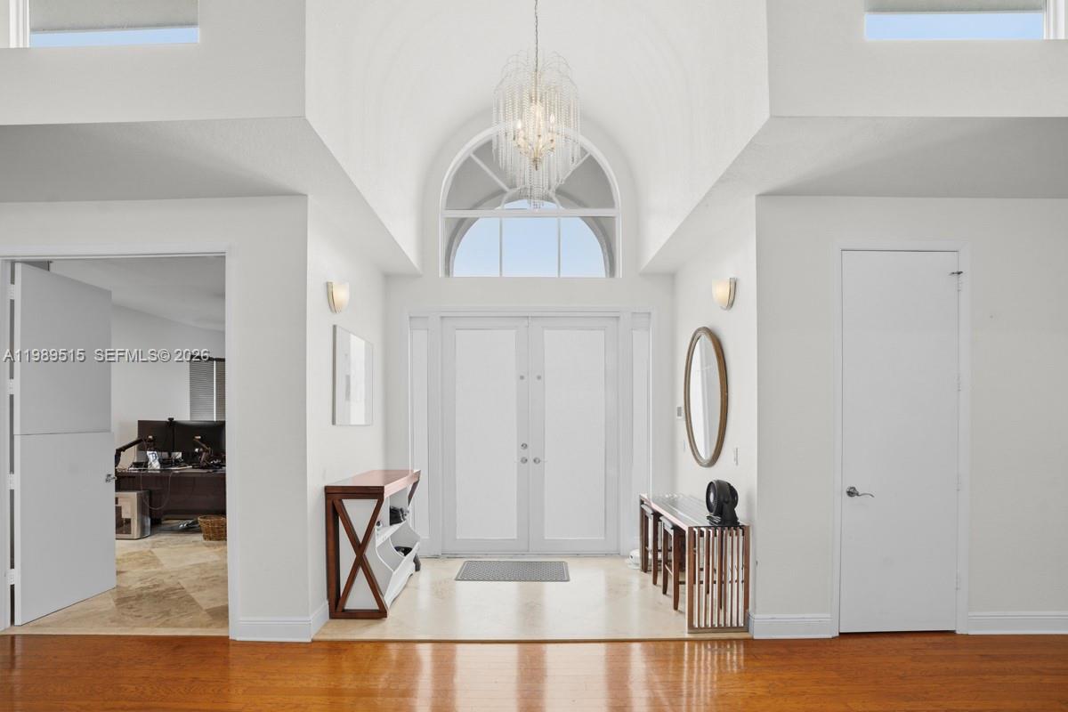 A bright entryway features a double-door entrance, a crystal chandelier, and light-colored tile flooring — 8179 Lakeview Dr, West Palm Beach FL 33412, WEST PALM BEACH, FL