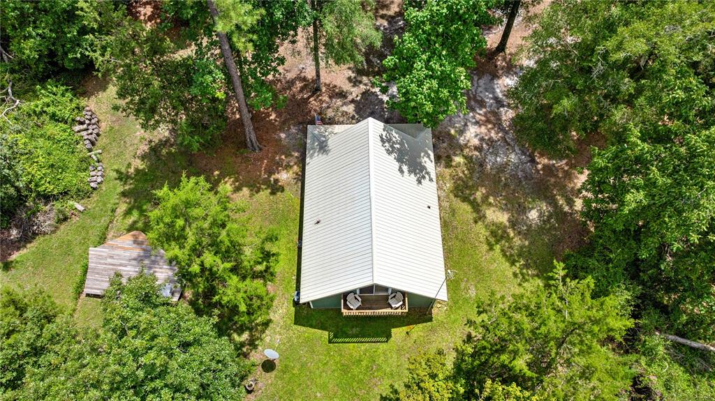 An aerial view shows a cabin with a metal roof surrounded by trees and grass — 694 SW QUARTER LANE, FORT WHITE, FL