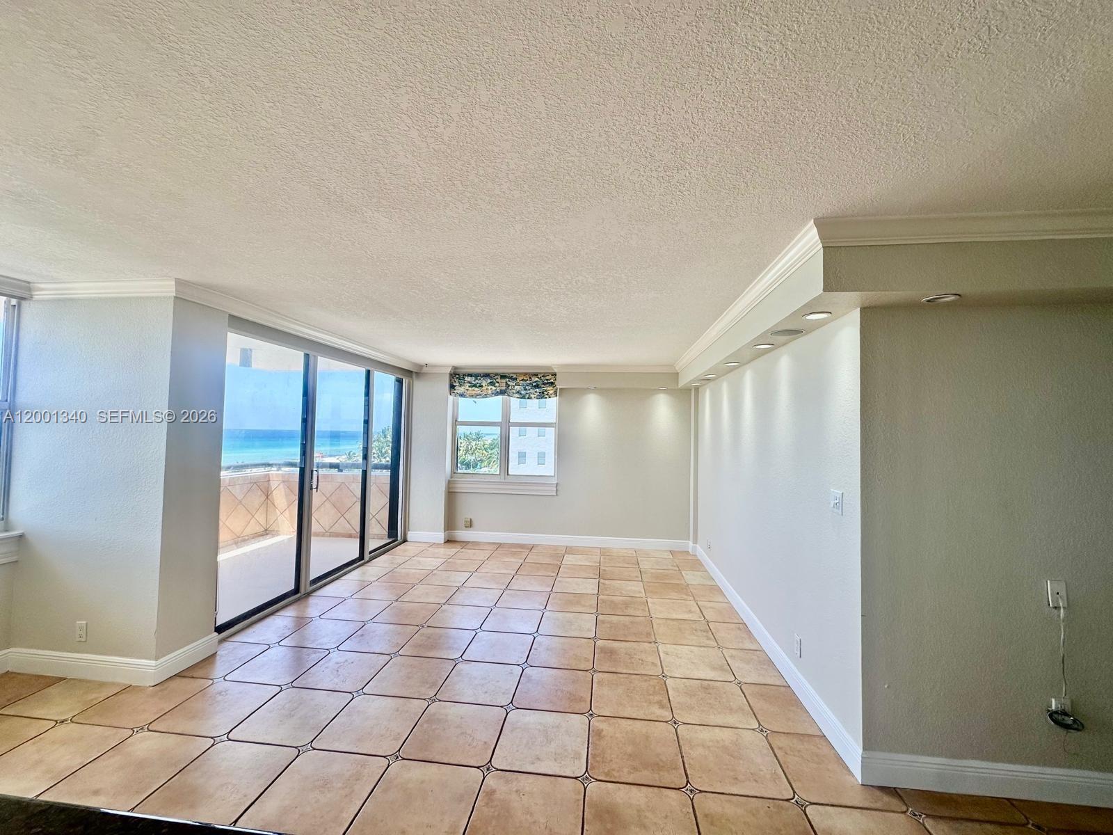 An empty room features beige tile flooring, recessed lighting, and a sliding glass door balcony — 2555 Collins Ave # 711, Miami Beach FL 33140, MIAMI BEACH, FL