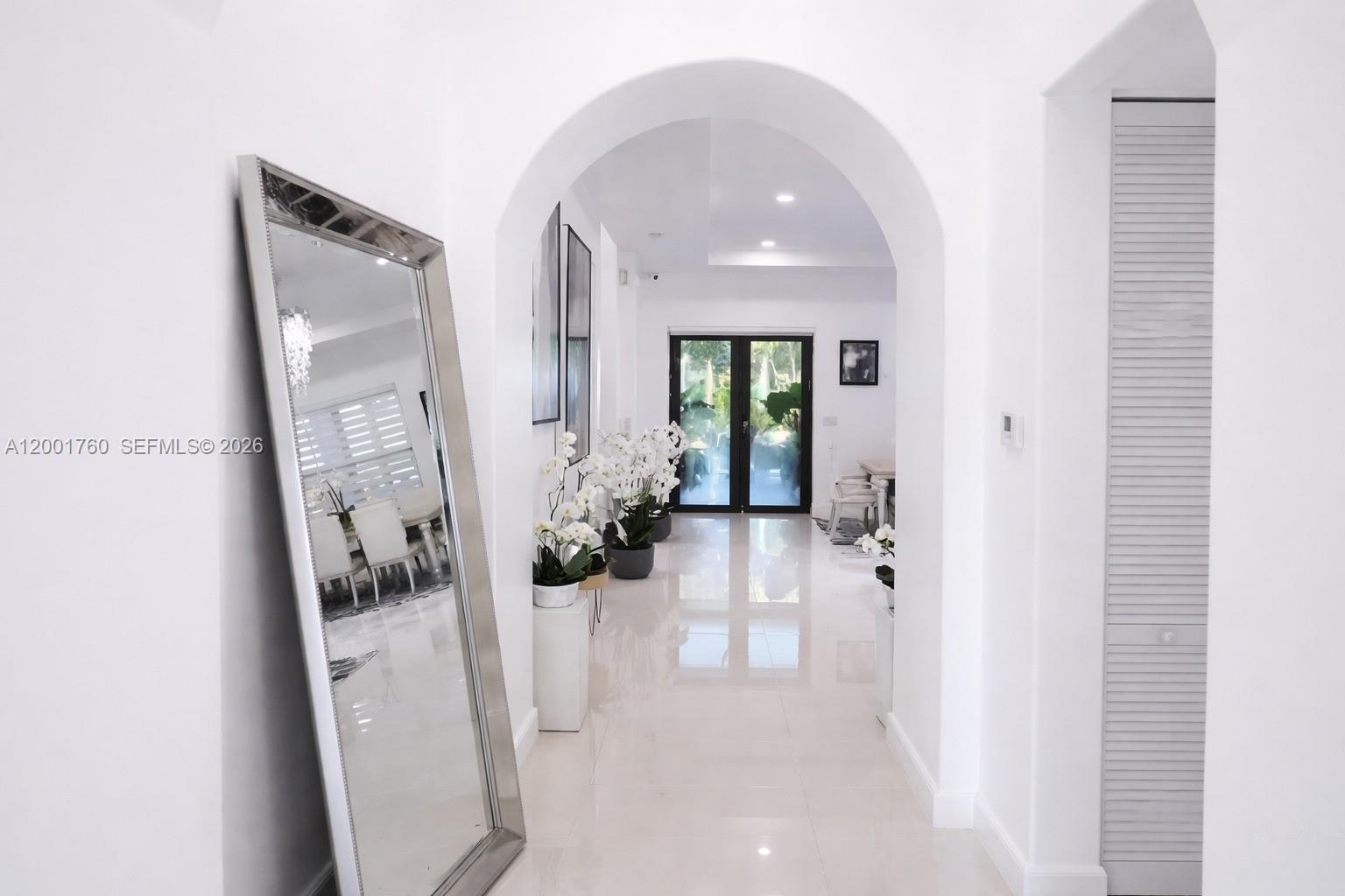 A bright white hallway features a large floor mirror, arched entryway, and polished tile floors — 8537 NW 39th Ct, Cooper City FL 33024, COOPER CITY, FL