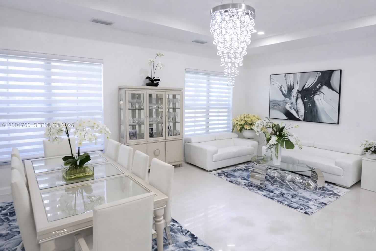 A bright dining and living area features white furniture, a crystal chandelier, and blue-patterned rugs — 8537 NW 39th Ct, Cooper City FL 33024, COOPER CITY, FL
