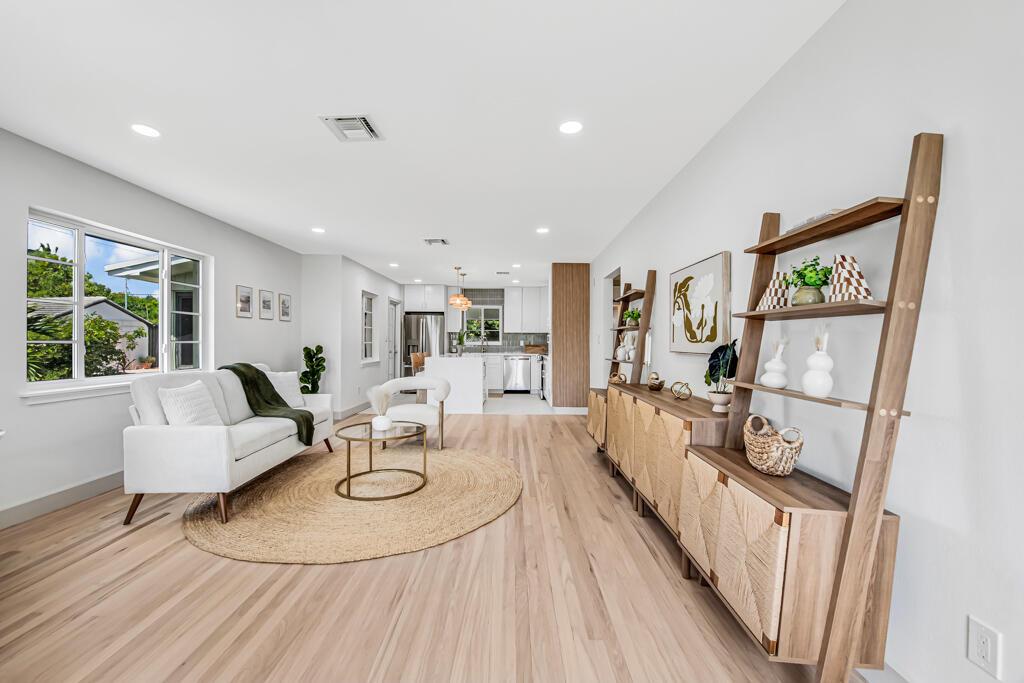A bright living room features light wood floors, a white sofa, and a wooden ladder shelf — 1201 N Palmway, FL 33460, FL