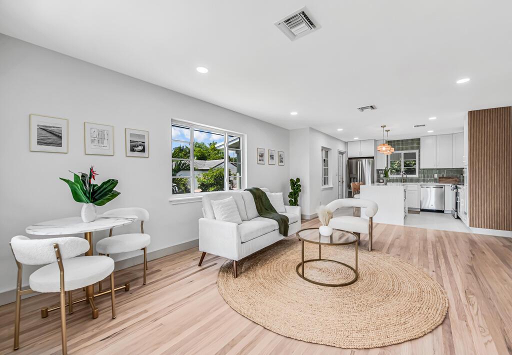 An open-concept living and dining area features light wood floors, white furniture, and a kitchen — 1201 N Palmway, FL 33460, FL