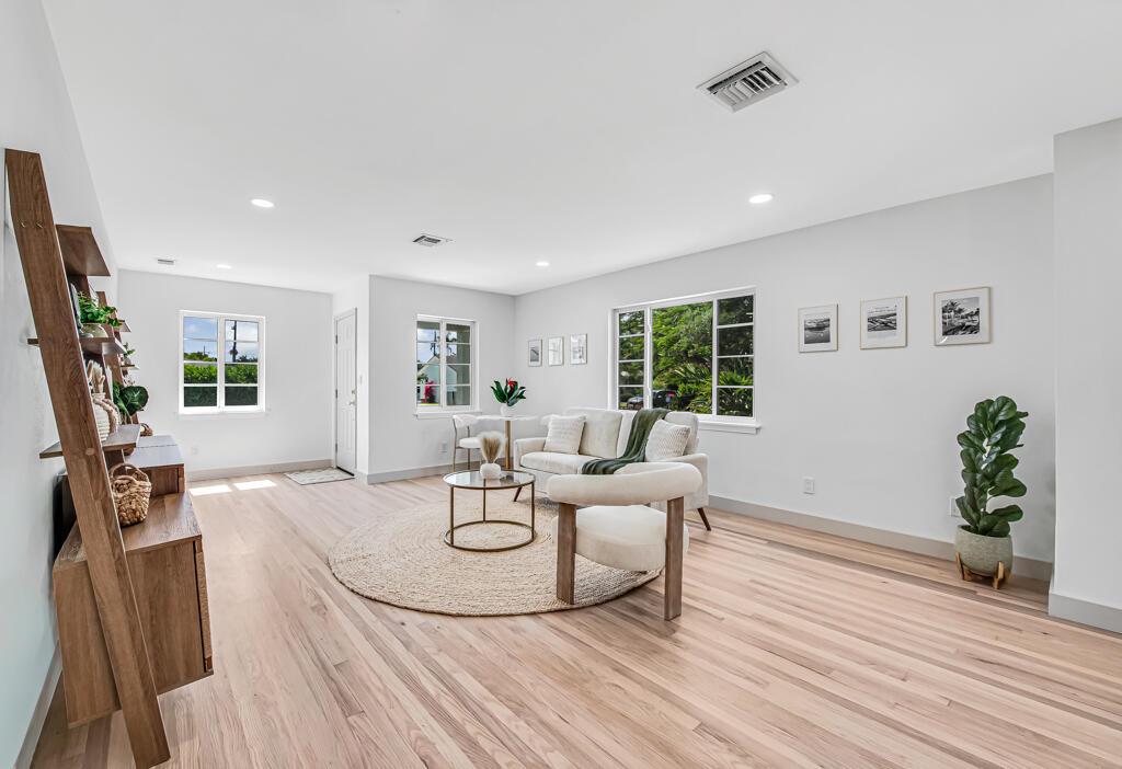 A bright living room features light wood flooring, a white sofa, and a circular rug — 1201 N Palmway, FL 33460, FL