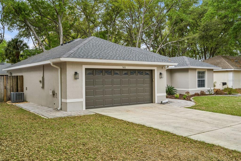 A beige single-story house with a two-car garage and a paved driveway — 165 QUAIL OAKS CIRCLE, GROVELAND, FL