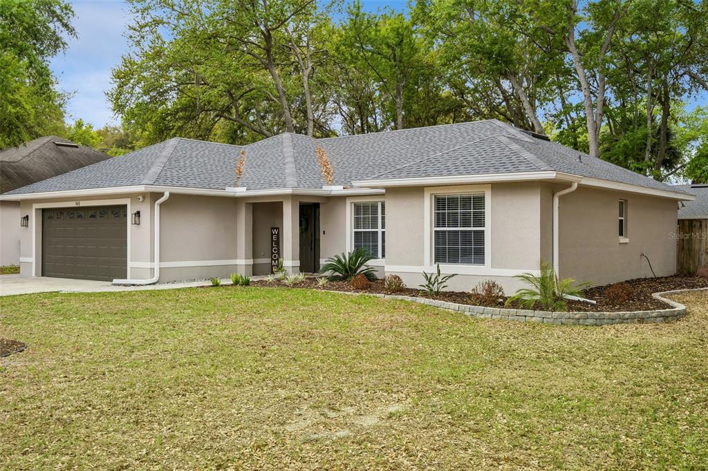 A single-story house with a gray roof, tan stucco exterior, and an attached two-car garage — 165 QUAIL OAKS CIRCLE, GROVELAND, FL