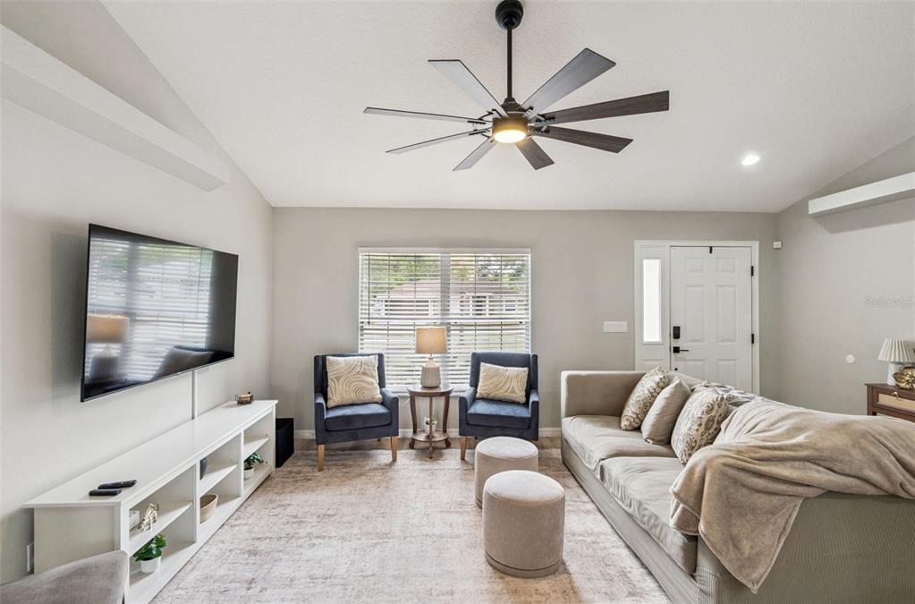 A living room features a ceiling fan, a wall-mounted television, two armchairs, and a sofa — 165 QUAIL OAKS CIRCLE, GROVELAND, FL
