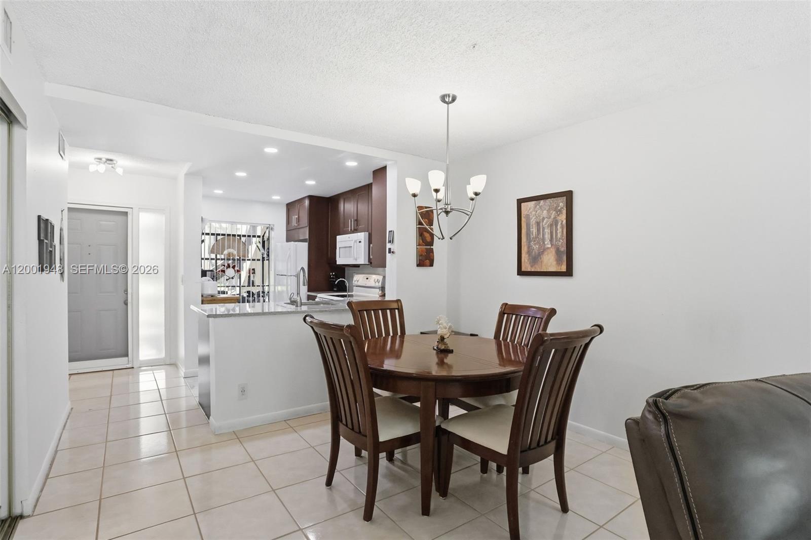 A dining area with a round wooden table and chairs sits beside an open kitchen — 2225 SW 15th St # 223, Deerfield Beach FL 33442, DEERFIELD BEACH, FL