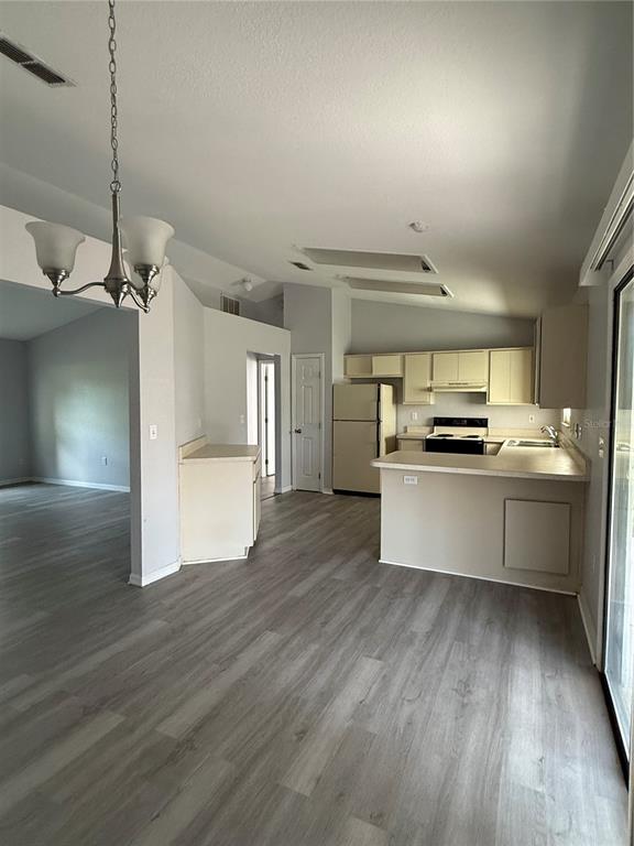An open-concept kitchen features light-colored cabinets, a breakfast bar, and gray wood-look flooring — 22 HEMLOCK TERRACE, OCALA, FL