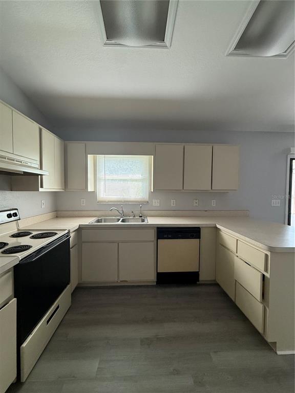 A kitchen features light-colored cabinets, a black stove, a dishwasher, and gray flooring — 22 HEMLOCK TERRACE, OCALA, FL