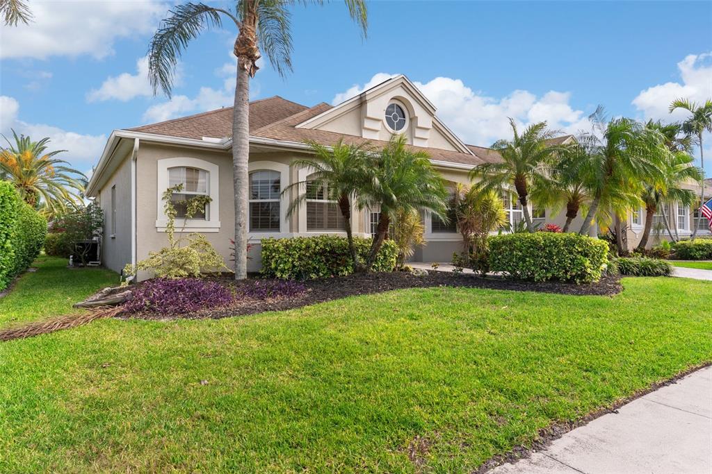 A single-story house with a beige exterior, a gabled roof, and several palm trees — 4516 SWORDFISH DRIVE, BRADENTON, FL