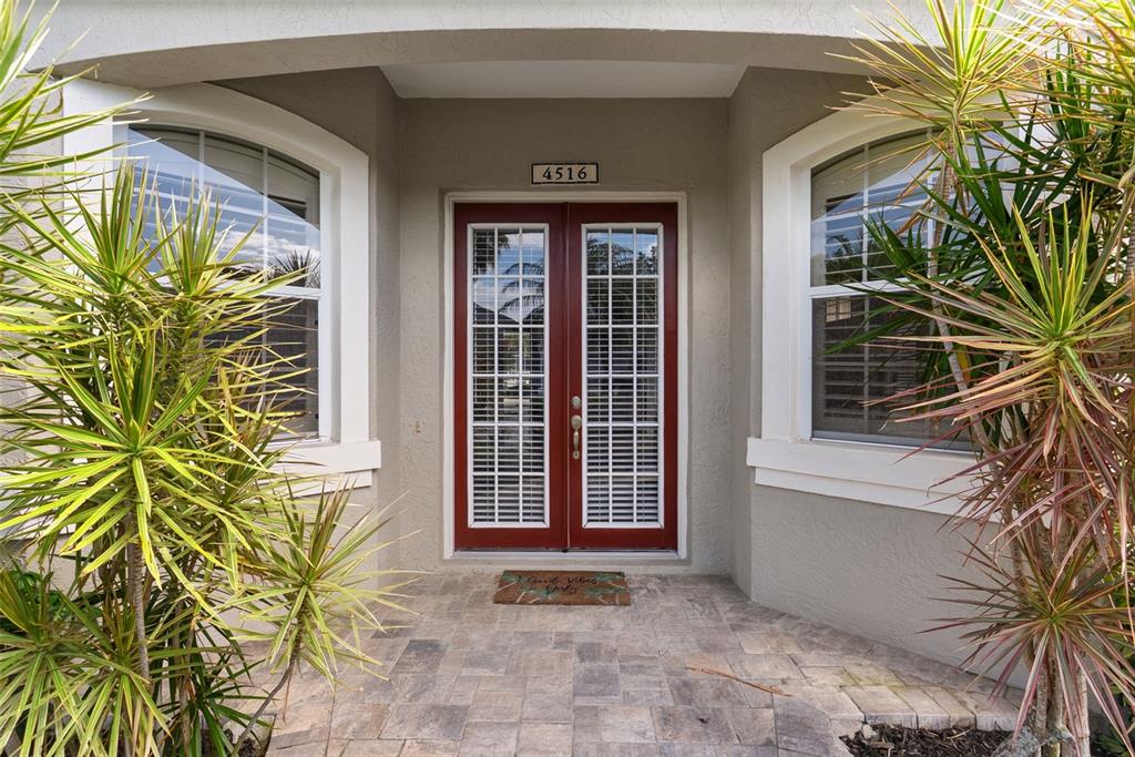 A front entryway features a red double door with glass panes and two arched windows — 4516 SWORDFISH DRIVE, BRADENTON, FL