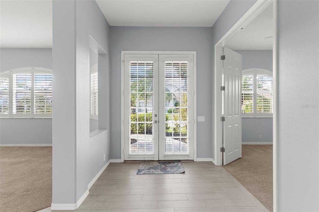 A bright entryway features light-colored tile flooring, double glass-paneled doors, and gray walls — 4516 SWORDFISH DRIVE, BRADENTON, FL